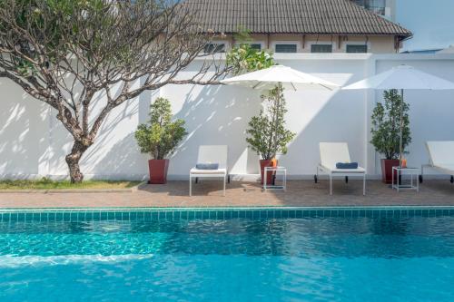 una piscina con sillas y sombrillas junto a un edificio en Le Charme Vientiane Hotel, en Vientiane