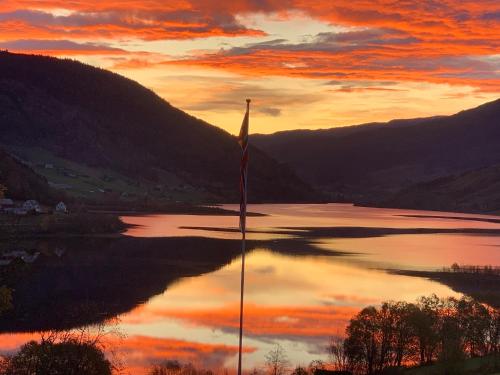 uma vista para um lago ao pôr-do-sol com uma bandeira em Lilandtunet Gjestgiveri em Liland