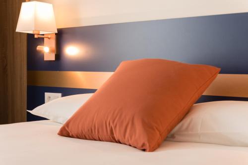 an orange pillow sitting on top of a bed at K Hotel in Strasbourg