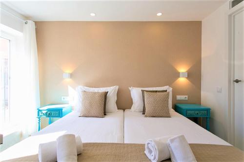 a bedroom with a large white bed with two blue tables at Suites Amália Guesthouse near Rossio Square in Lisbon