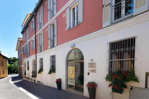 a red and white building with flowers in the window at Hotel Dei Tigli in Angera