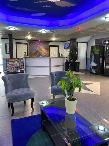 a lobby with two chairs and a table with a plant at R Nite Star Inn and Suites -Home of the Cowboys & Rangers in Arlington