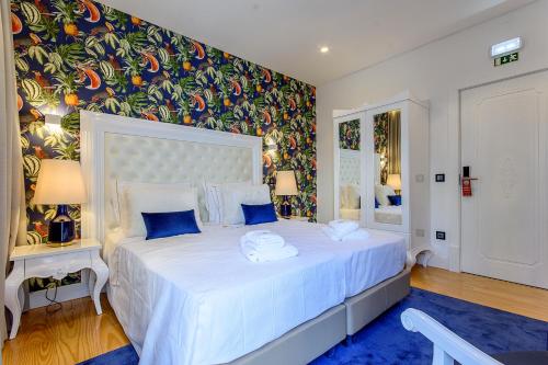 a bedroom with a large white bed with blue pillows at Villa Mariazinha Charming Hotel in Portimão