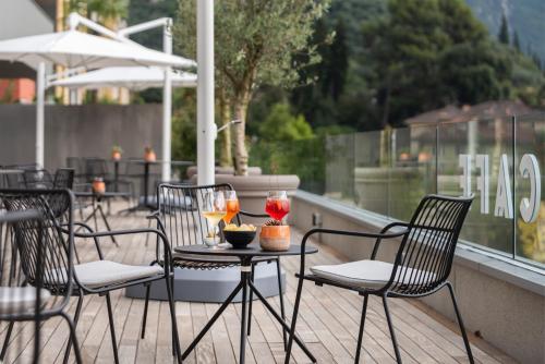 een tafel en stoelen op een balkon met drankjes erop bij HOODY ACTIVE & HAPPINESS HOTEL in Arco