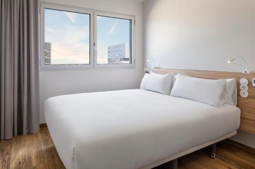 a white bed in a room with a window at B&B HOTEL Lisboa Aeroporto in Lisbon