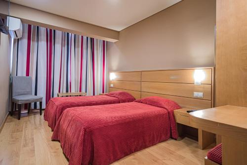 a hotel room with two beds with red sheets at Hotel Botanico in Lisbon