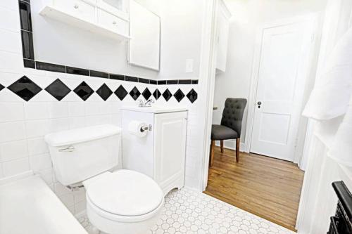 a white bathroom with a toilet and a chair at Dallas Native, Lower-Greenville Ave Area in Dallas