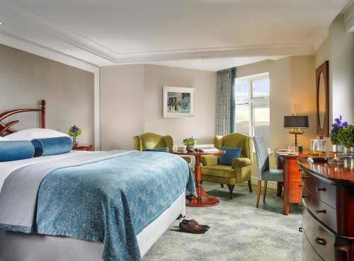 a bedroom with a bed and a desk and chairs at Killarney Randles Hotel in Killarney