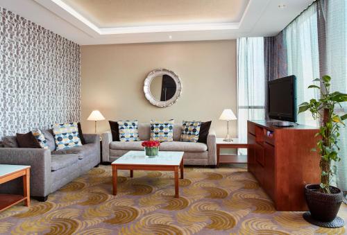 a living room with a couch and a tv at Holiday Inn Kuwait Al Thuraya City, an IHG Hotel in Kuwait