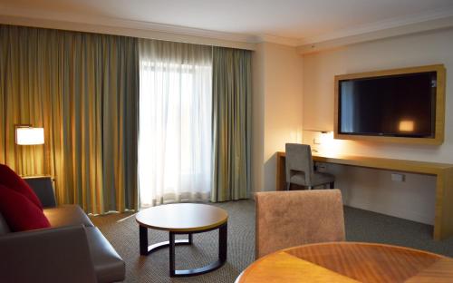 um quarto de hotel com televisão e sala de estar em Stamford Plaza Sydney Airport Hotel & Conference Centre em Sidney