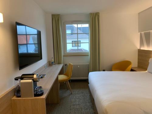 a hotel room with a bed and a television at Hôtel Restaurant Au Boeuf in Blaesheim