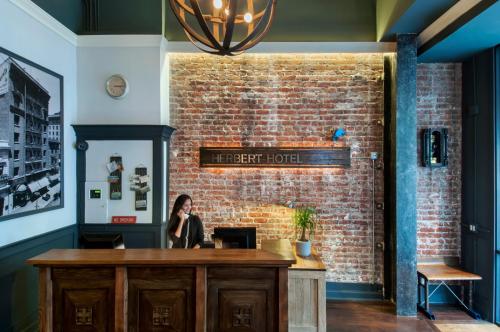 a woman sitting at a desk in front of a brick wall at Herbert Hotel in San Francisco