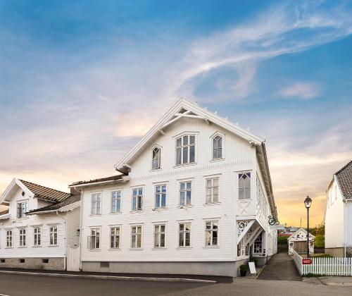 un edificio bianco con finestre su strada di Lillesand Hotel Norge a Lillesand