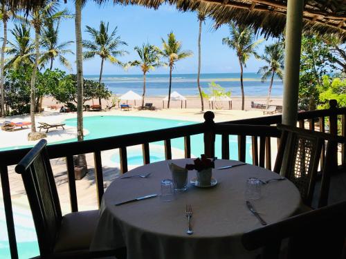 uma mesa numa varanda com vista para a praia em White Elephant Sea Lodge em Melinde