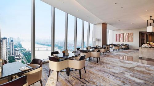 een restaurant met tafels en stoelen en grote ramen bij InterContinental Guangzhou Exhibition Center, an IHG Hotel - Free shuttle between hotel and Exhibition Center during Canton Fair & Exhibitor registration Counter in Guangzhou