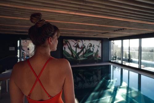 una donna in costume da bagno in piedi accanto alla piscina di VALO Hotel & Work Helsinki a Helsinki