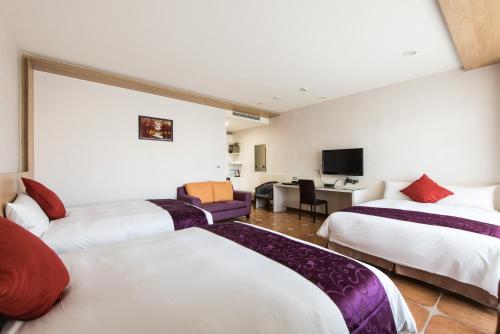 a hotel room with three beds and a desk at Kending Kaying Hotel in Hengchun South Gate