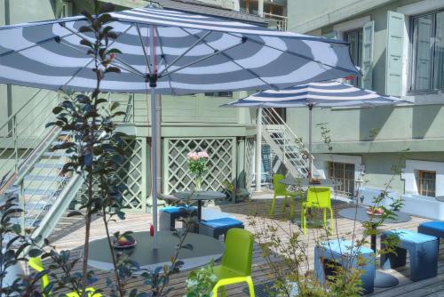 a patio with two blue umbrellas and chairs and tables at Campanile Annecy Centre - Gare in Annecy