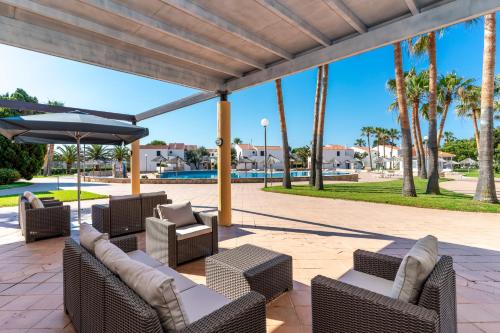 een patio met stoelen, een parasol en palmbomen bij Apartamentos Vistapicas in Cala en Blanes