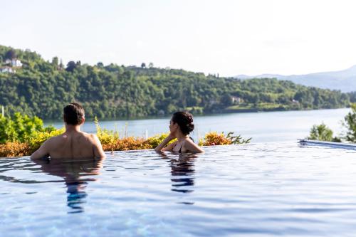 a man and a woman sitting in a swimming pool at Hotel de Charme Laveno in Laveno-Mombello