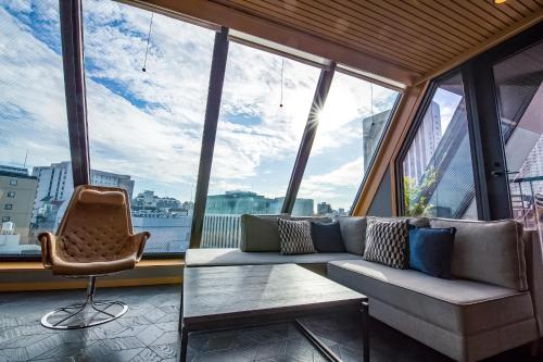 a room with a couch and a chair in front of windows at Asakusa Kokono Club Hotel in Tokyo