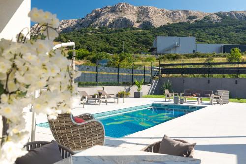 une piscine avec des chaises longues et une montagne en arrière-plan dans l'établissement Villa Aurora, à Baška