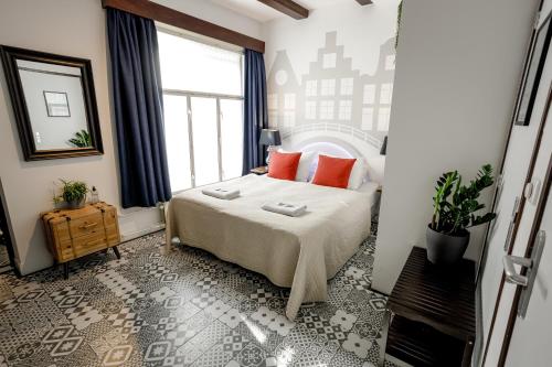 a bedroom with a bed with red pillows and a window at Aris Amsterdam in Amsterdam