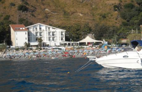 a boat in the water next to a beach at Hotel Mareblu in Amantea