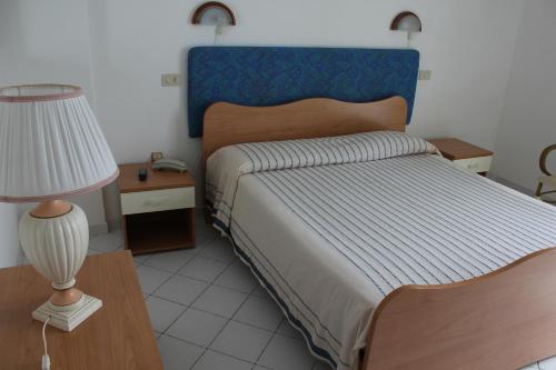 a bedroom with a bed with a blue headboard and a lamp at Hotel Mareblu in Amantea