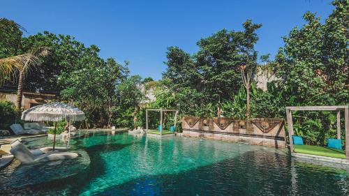 een zwembad in een resort met een parasol en stoelen bij Amnaya Resort Nusa Dua in Nusa Dua