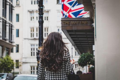 a woman walking down a street with a british flag at The May Fair, A Radisson Collection Hotel, Mayfair London in London