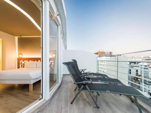 a room with a balcony with a bed and chairs at Ibis Styles Lisboa Centro Marquês de Pombal in Lisbon