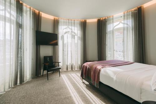 Habitación de hotel con cama, silla y ventanas en 1908 Lisboa Hotel, en Lisboa