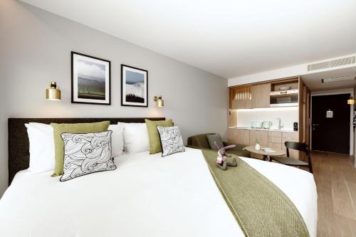 um quarto com uma grande cama branca com almofadas verdes em Wilde Aparthotels London Paddington em Londres