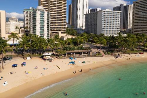 a beach with people in the water and buildings at Aston Waikiki Circle Hotel in Honolulu