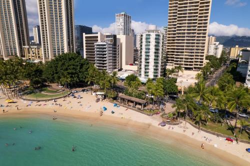 a beach in a city with people in the water at Aston Waikiki Circle Hotel in Honolulu