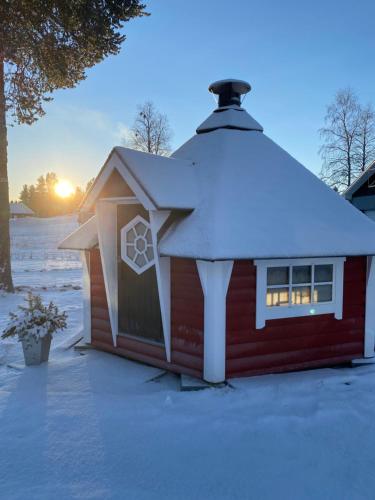 une maison rouge avec un toit recouvert de neige dans l'établissement Modern Lapland Cottage with Outdoor Sauna & BBQ Hut, à Slagnäs