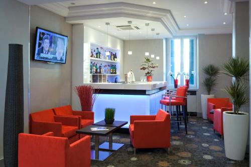 a waiting room with red chairs and a bar at Allobroges Park Hôtel in Annecy