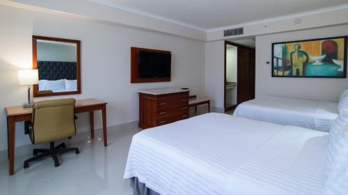 a hotel room with two beds and a desk and a computer at Holiday Inn Tuxtla Gutierrez, an IHG Hotel in Tuxtla Gutiérrez