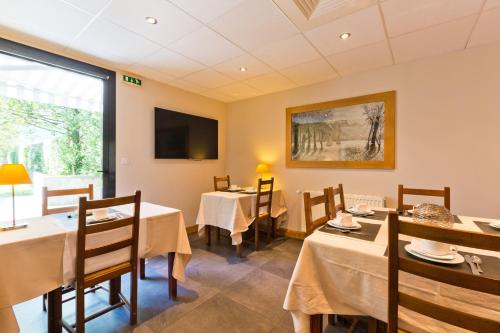 a dining room with tables and a tv at Hotel Les Terrasses in Annecy