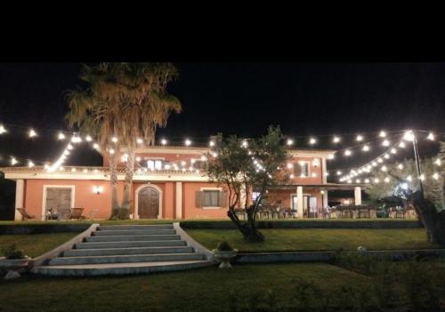 un grand bâtiment avec des lumières allumées la nuit dans l'établissement Casale degli Ulivi, à Cirò Marina