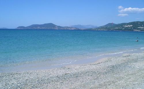 una spiaggia con acqua blu e montagne sullo sfondo di Studio proche de la plage de l'almanarre a Hyères