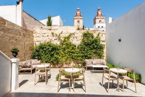 un patio con tavoli e sedie di fronte a una parete di Fragile Hotel a Ciutadella