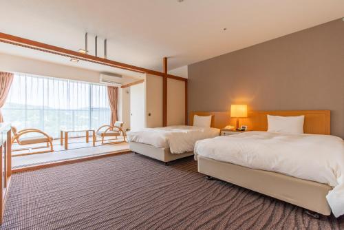 a hotel room with two beds and a window at Wisterian Life Club Usami in Ito