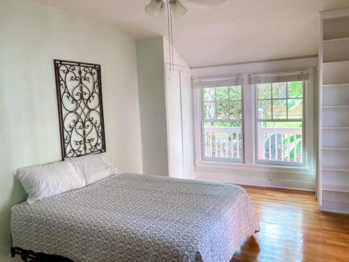 a bedroom with a bed and two windows at University House - 8 Bedrooms Walk to UF / Stadium in Gainesville