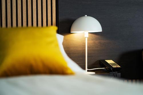 lampa siedząca na nocnym stoliku obok łóżka w obiekcie Konvin Hotel by Reykjavik Keflavik Airport w Keflavíku