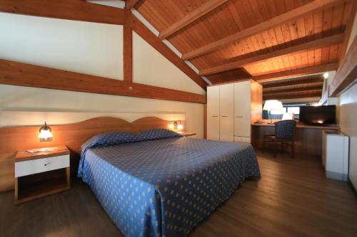 een slaapkamer met een blauw bed en een bureau bij Hotel Eden in Valeggio sul Mincio