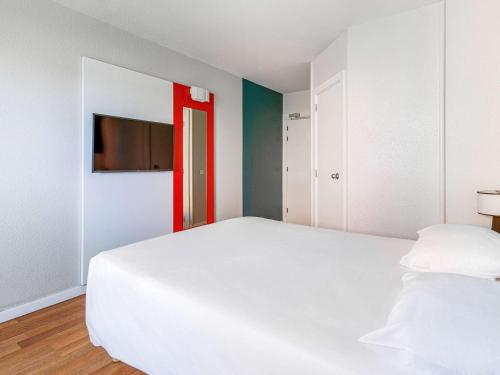 um quarto com uma cama branca e uma porta vermelha em ibis Strasbourg Centre Historique em Estrasburgo