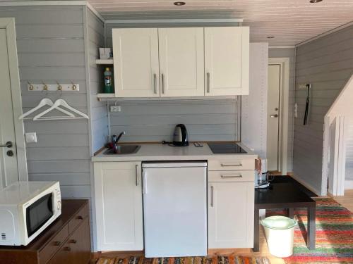 a kitchen with white cabinets and a microwave at Anneks i naturskjønne Gitlevåg in Lyngdal