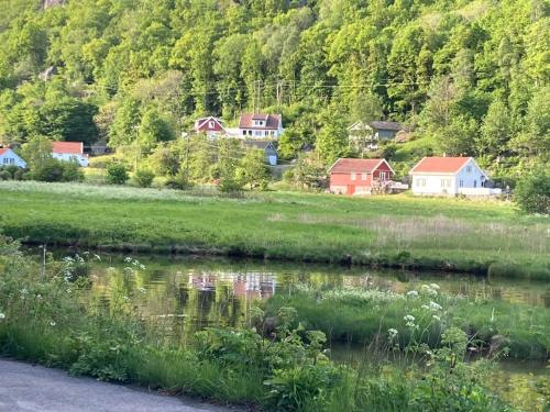 a small village next to a river with houses at Anneks i naturskjønne Gitlevåg in Lyngdal